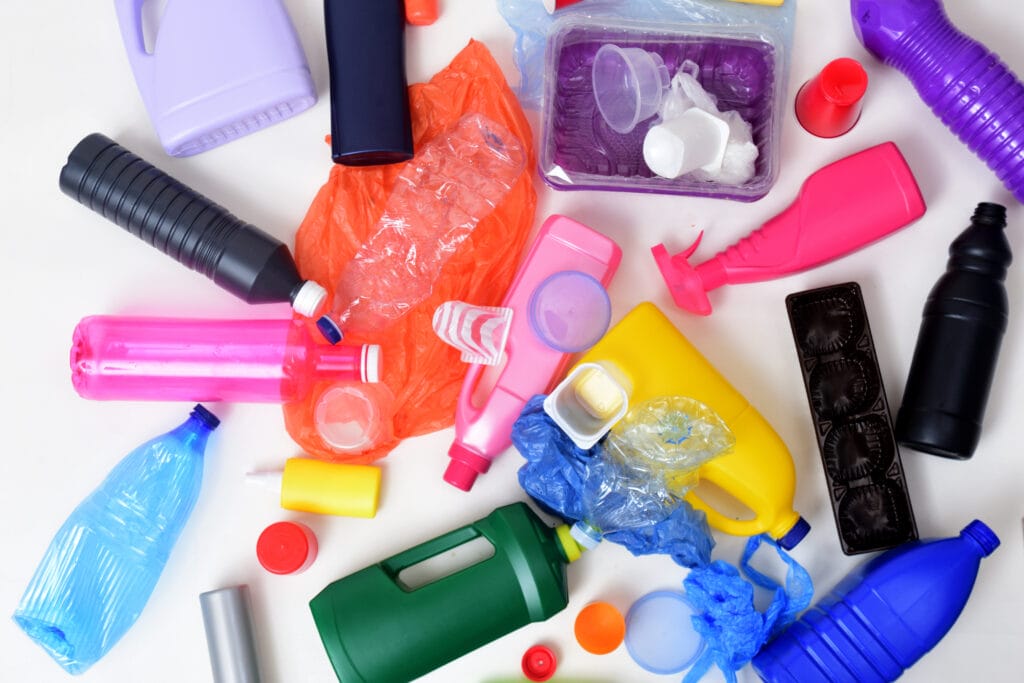 Various colorful plastic bottles, containers, and packaging scattered on a white background.