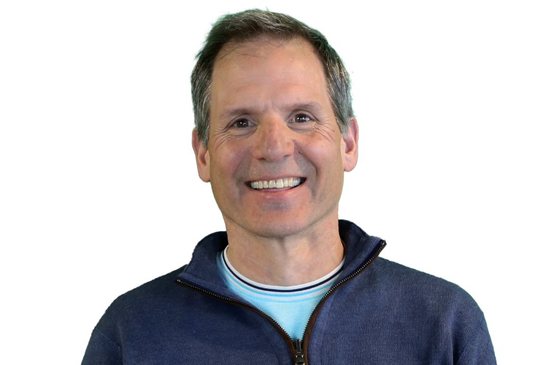 Smiling man in a blue sweater standing in front of a green background.